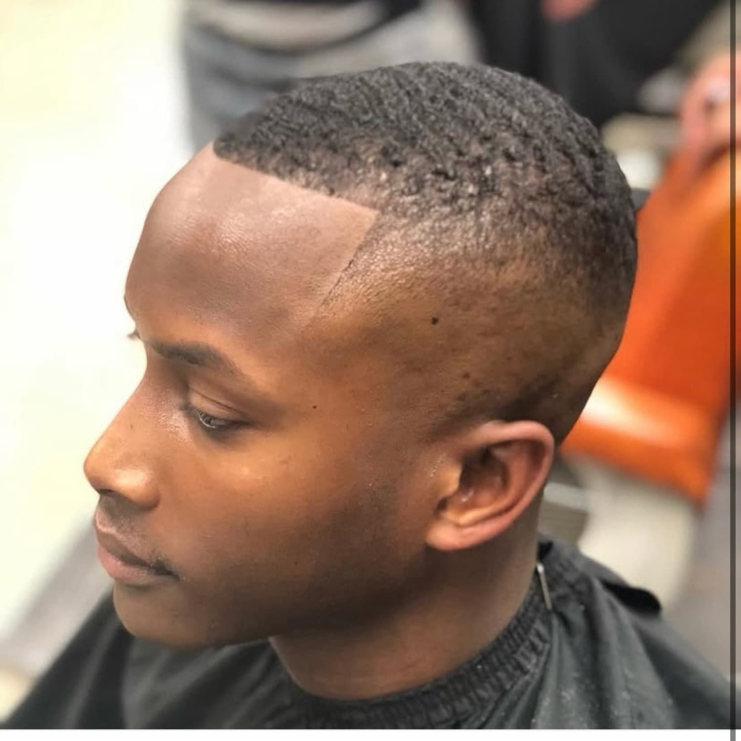 High skin fade with a crisp angled lineup.