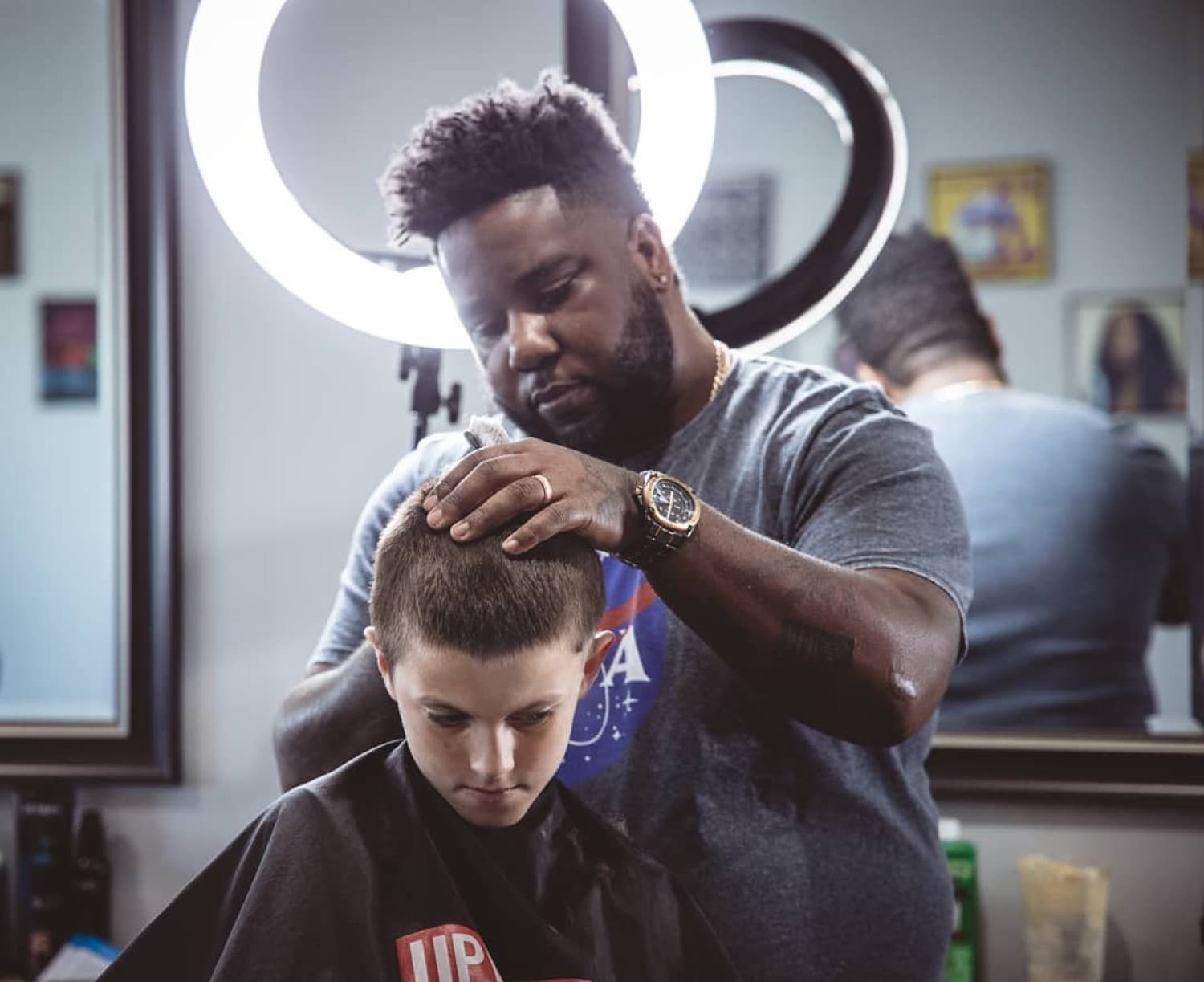 V the Barber lining up a fresh fade under the ring light.